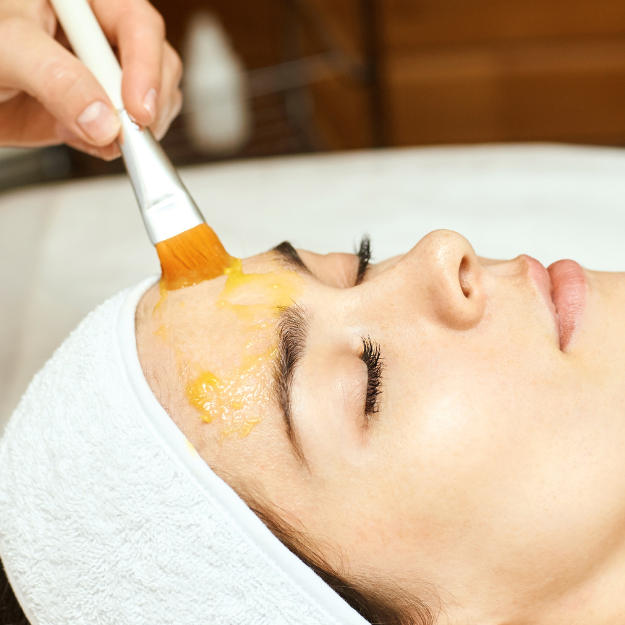 persona recibiendo tratamiento facial peeling químico con una brocha en la frente